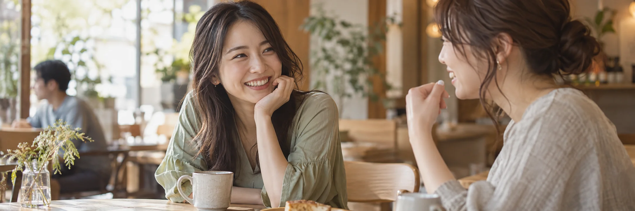 カフェで笑顔を見せながら話す女性2人
